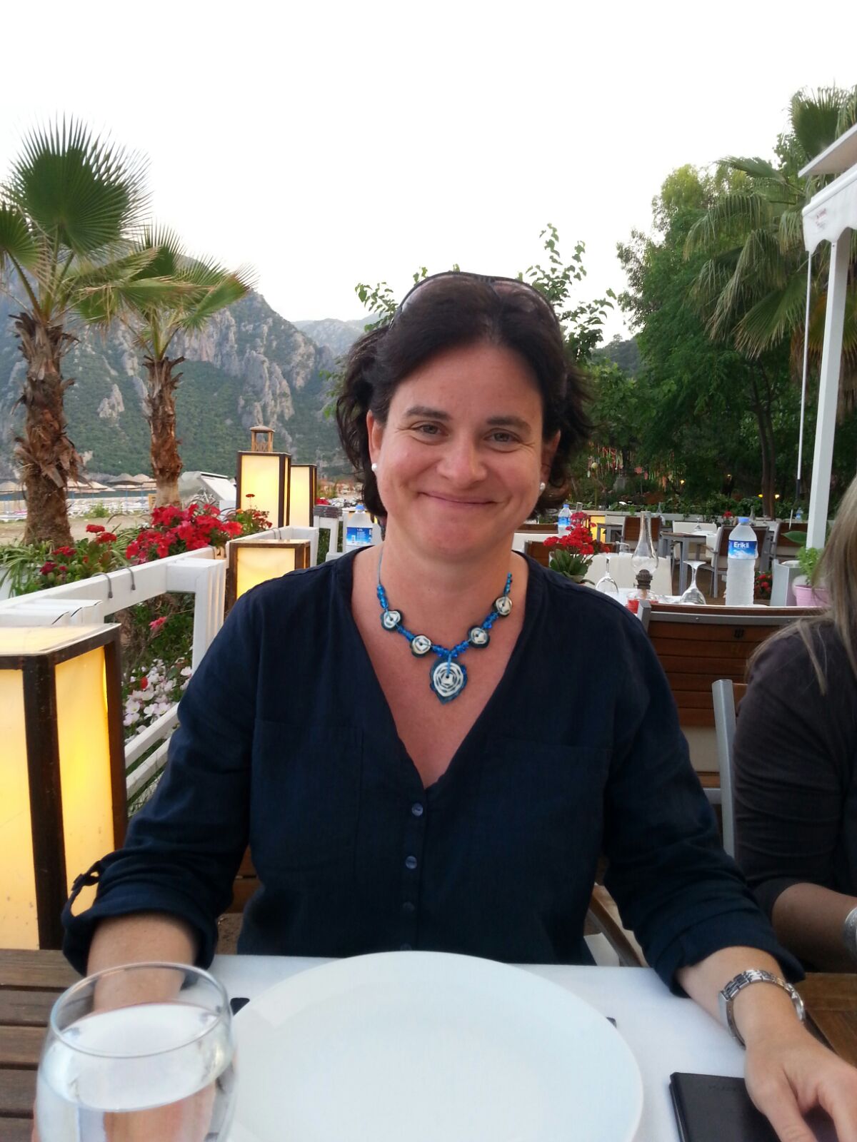 Ines de Vera Ines sitzt an einem Tisch in einem Restaurant draußen in der Natur und strahlt mich an.