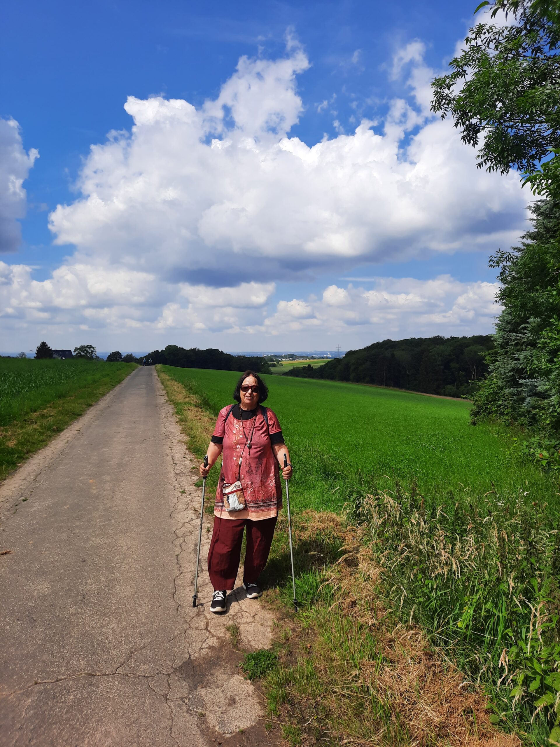 Bauernhofweg Zamyat auf einem Weg mit Walkstöcken, blauer Himmel mit weißen Wolken