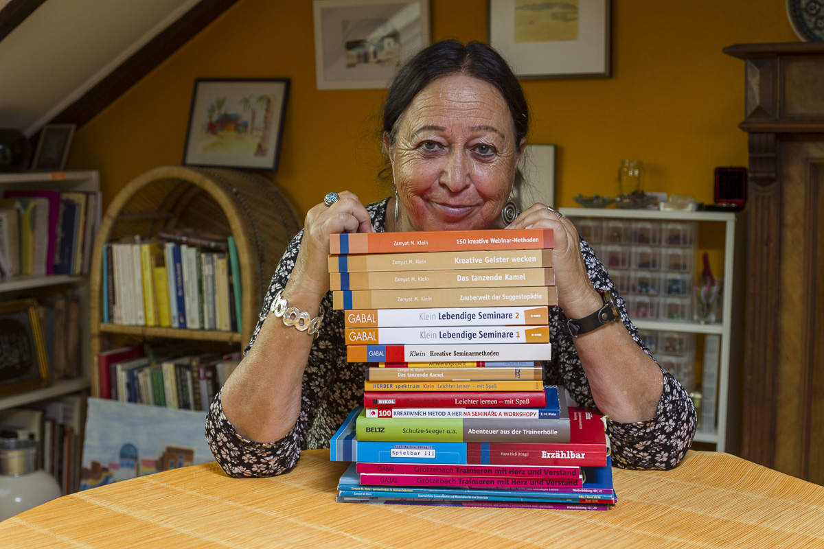 Zamyat hat vor sich einen Stapel ihrer 22 Bücher liegen
